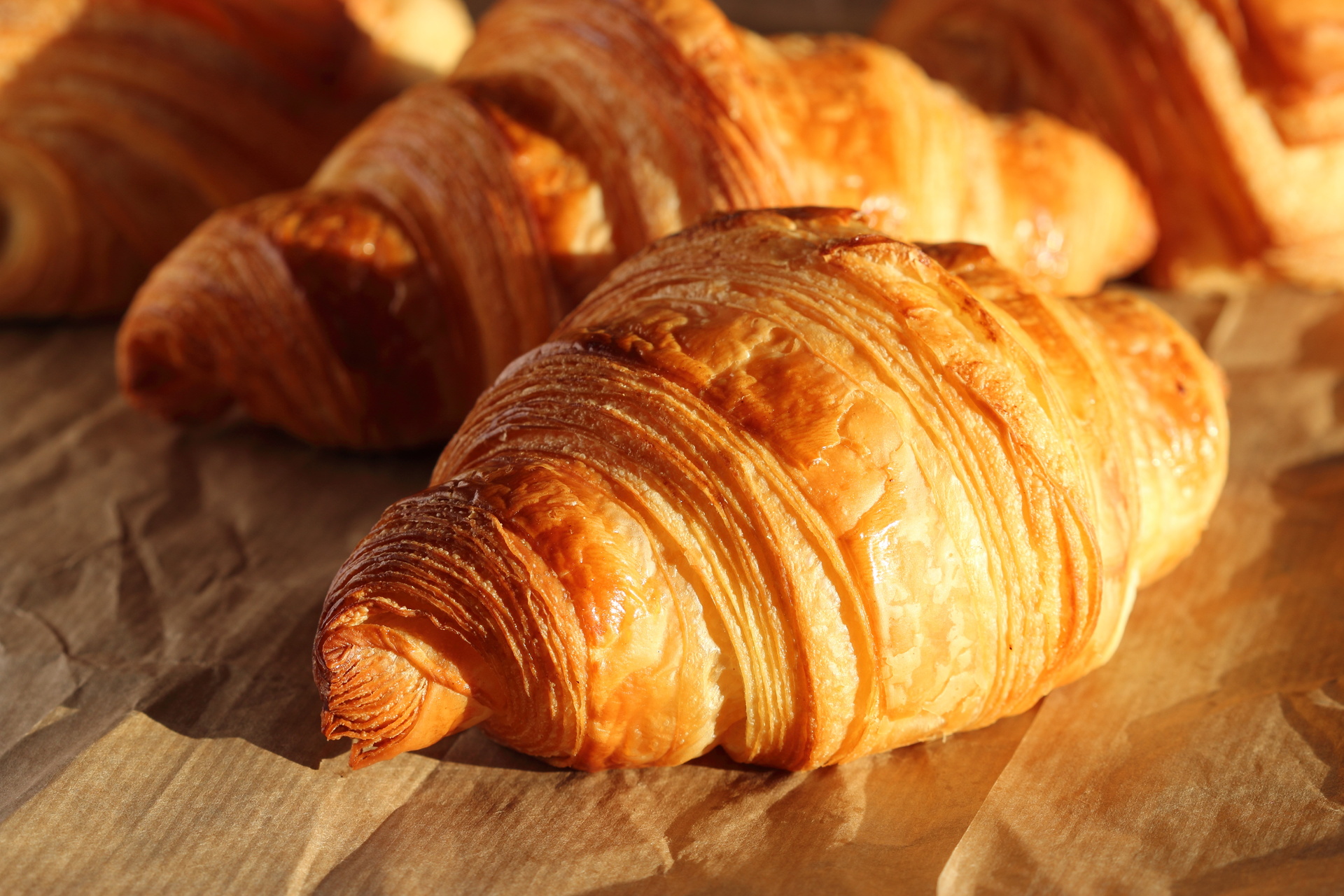 Fresh golden croissants with flaky layers on parchment paper