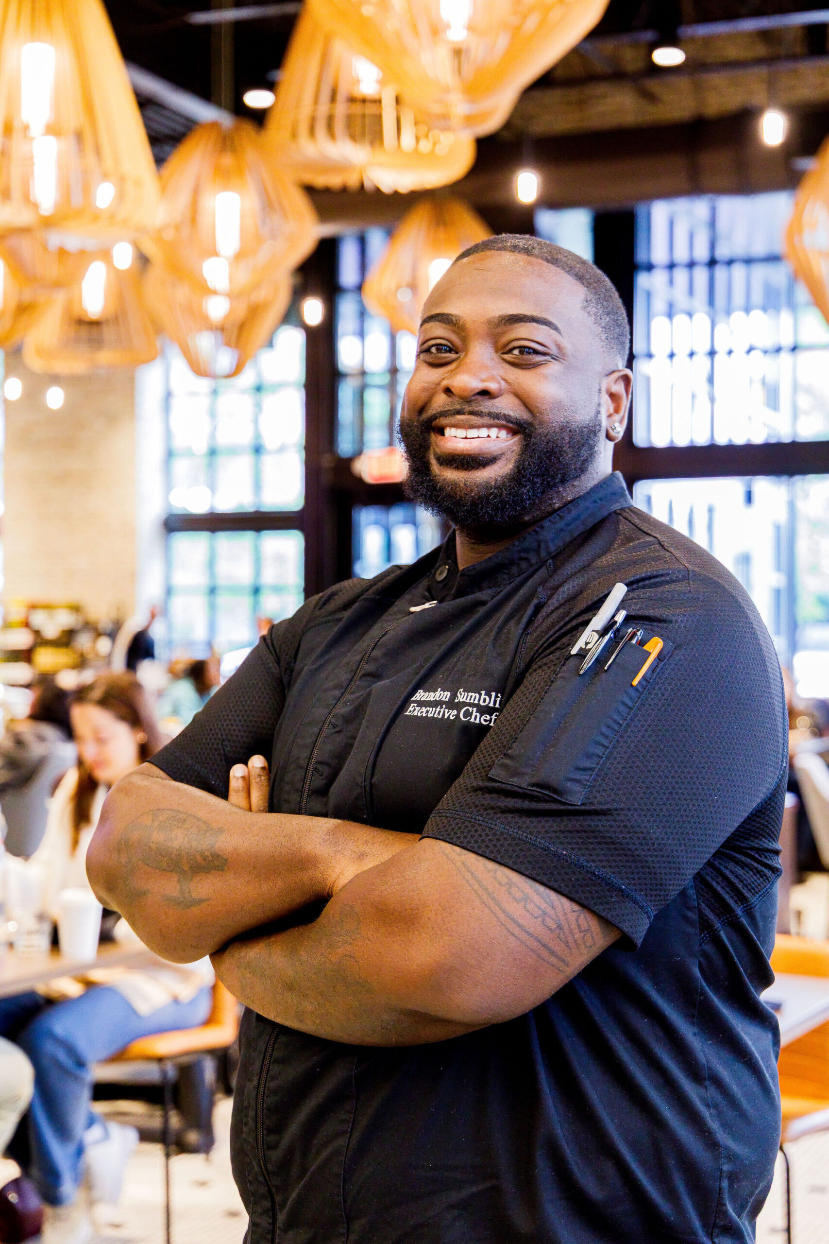 Chef Brandon Sumblin, Executive Chef for Kneads Bake Shop’s Logan Circle location, smiling inside a restaurant.
